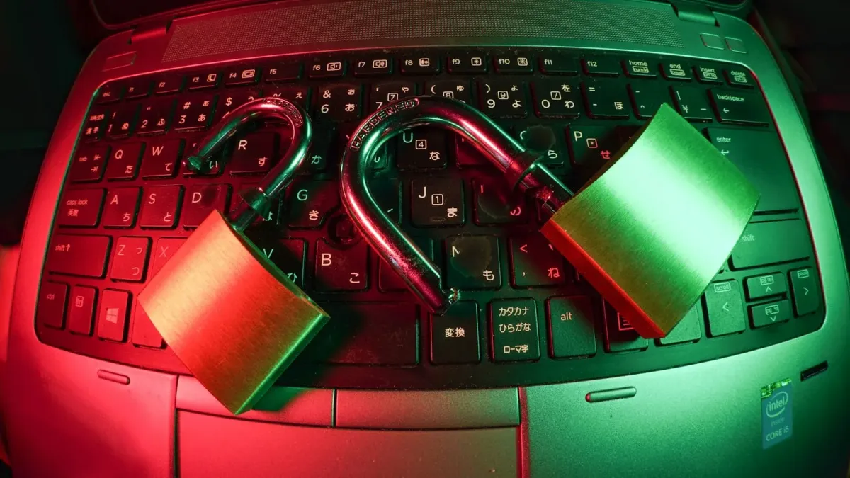 Zwei geöffnete Vorhängeschlösser liegen auf einer Laptop-Tastatur, rot und grün ausgeleuchtet