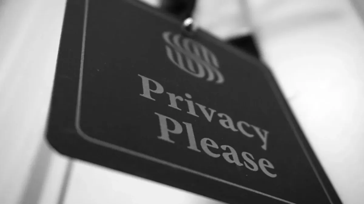 Schwarz-weiß-Aufnahme eines Türanhängers mit der Aufschrift »Privacy Please«