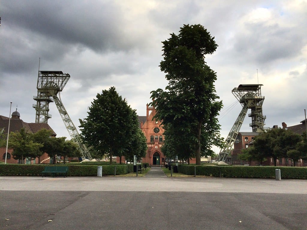 Zeche Zollern in Dortmund: Backsteingebäude zwischen zwei Fördergerüsten unter Wolkenhimmel