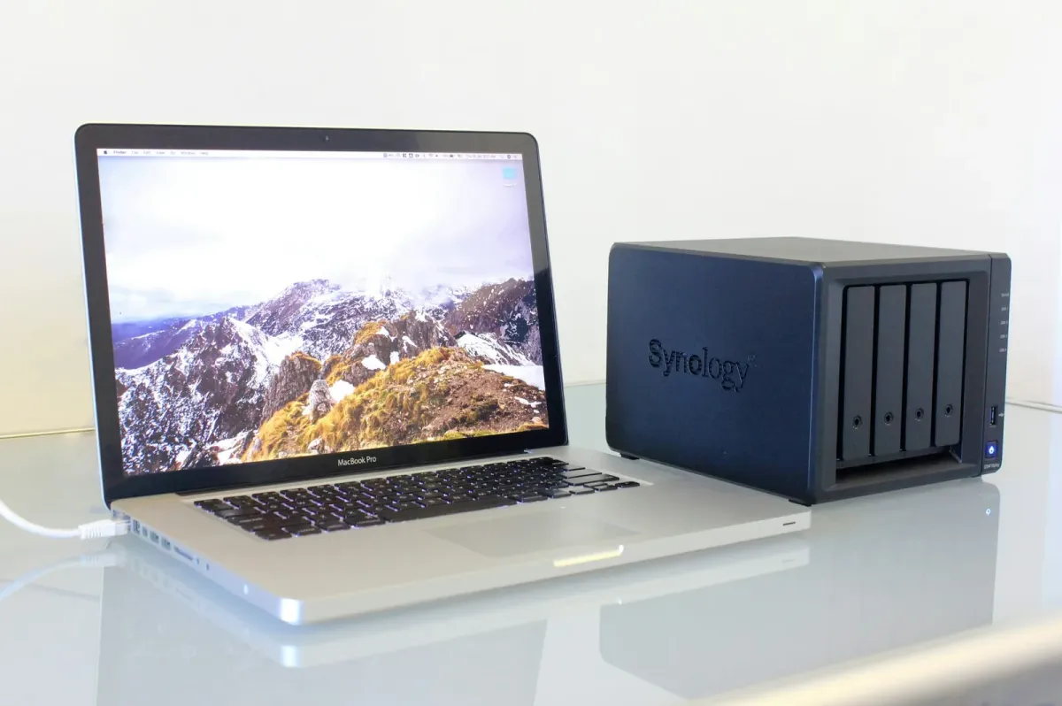 Notebook neben einem NAS-Gehäuse mit vier Festplatteneinschüben auf einem Schreibtisch