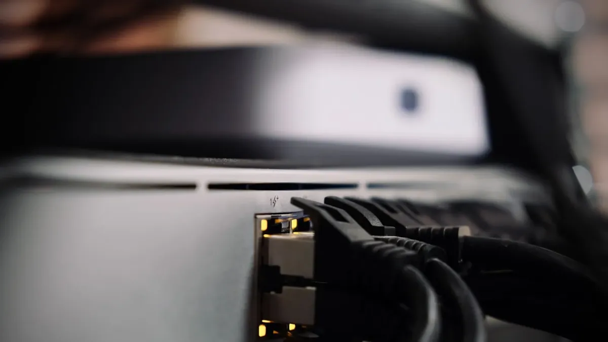 Zwei Netzwerkkabel stecken in den Anschlüssen eines grauen Netzwerkgeräts, die Status-LEDs leuchten gelb