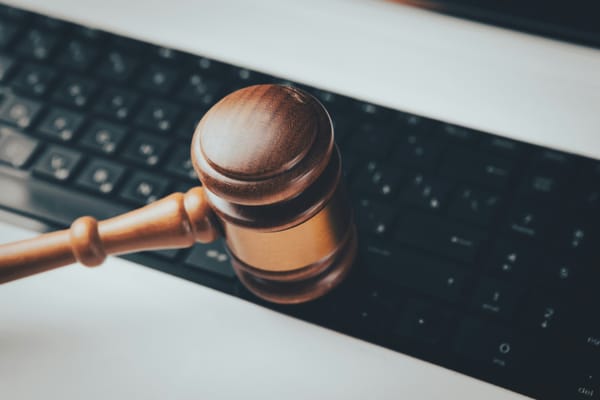Richterhammer aus Holz liegt quer auf der Tastatur eines aufgeklappten Laptops