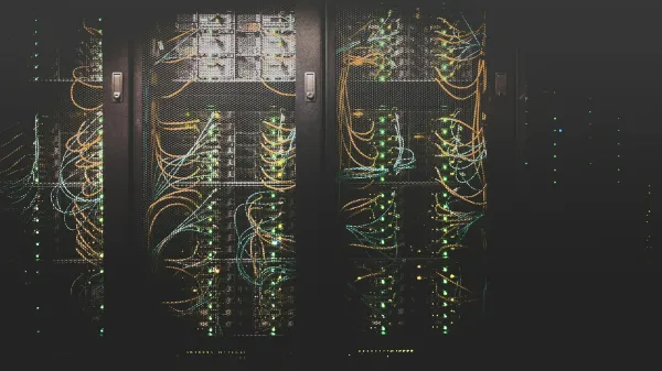 Dunkler Serverraum mit Racks voller Netzwerkkabel und grün leuchtender Status-LEDs