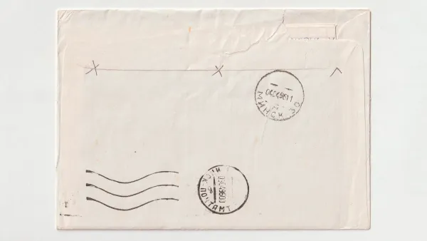 Rückseite eines zugeklebten, zerknitterten Briefumschlags mit zwei runden Poststempeln und Wellenlinien