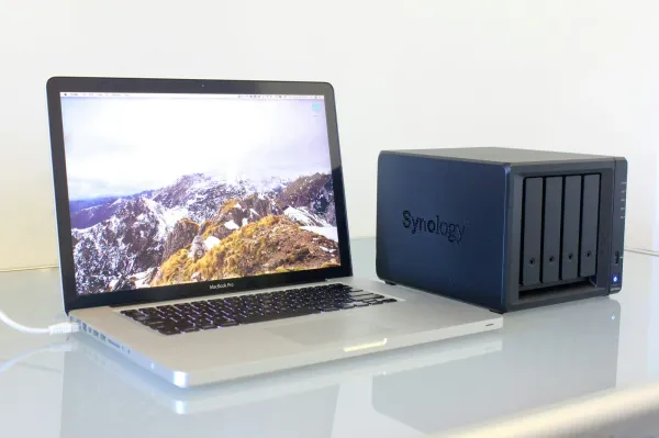 Notebook neben einem NAS-Gehäuse mit vier Festplatteneinschüben auf einem Schreibtisch