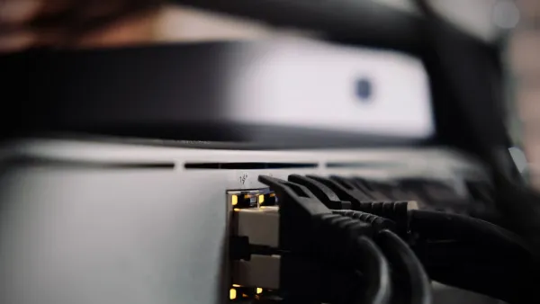 Zwei Netzwerkkabel stecken in den Anschlüssen eines grauen Netzwerkgeräts, die Status-LEDs leuchten gelb
