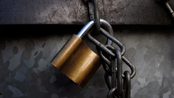 Messing-Vorhängeschloss an einer schweren Stahlkette vor einer verwitterten Metallwand