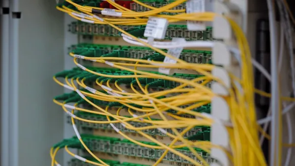 Glasfaser-Patchfeld im Netzwerkschrank, grüne Stecker in nummerierten Reihen und gelbe Kabel kreuz und quer