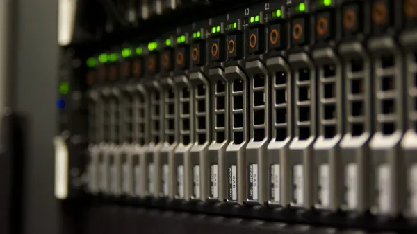 Nahaufnahme eines Serverschranks mit einer Reihe eingeschobener Festplatten und grün leuchtenden Status-LEDs